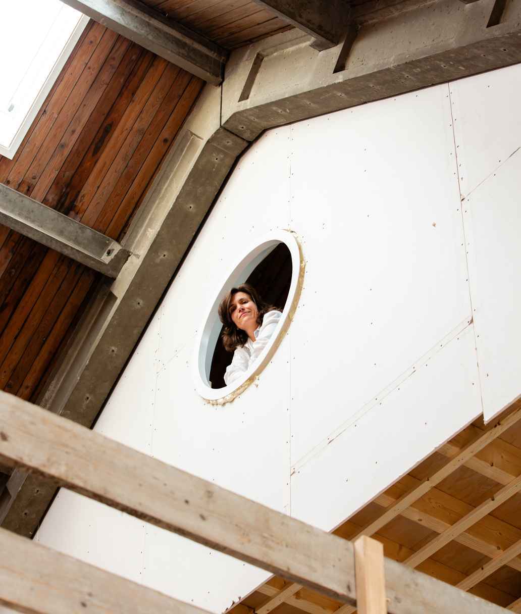 Architect Sanne Oomen kijkt uit een raam naar beneden.
